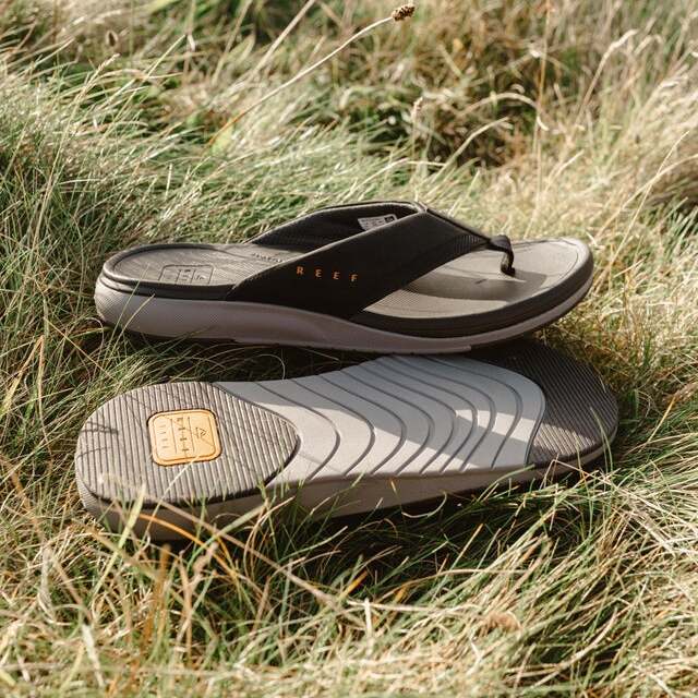 Cushion Norte men's black surf-inspired flip flops with anatomical arch support facing right on grass outdoors