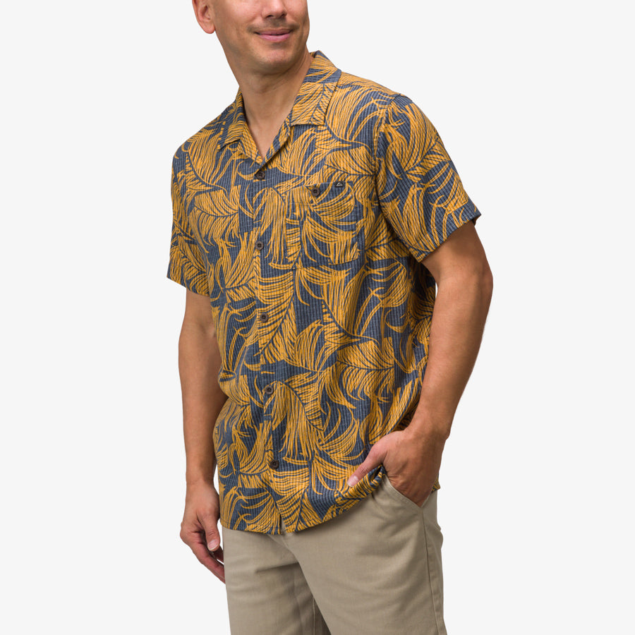 Man wearing Kantis Shirt with yellow and blue leaf pattern, styled for beach-inspired comfort and active lifestyle.
