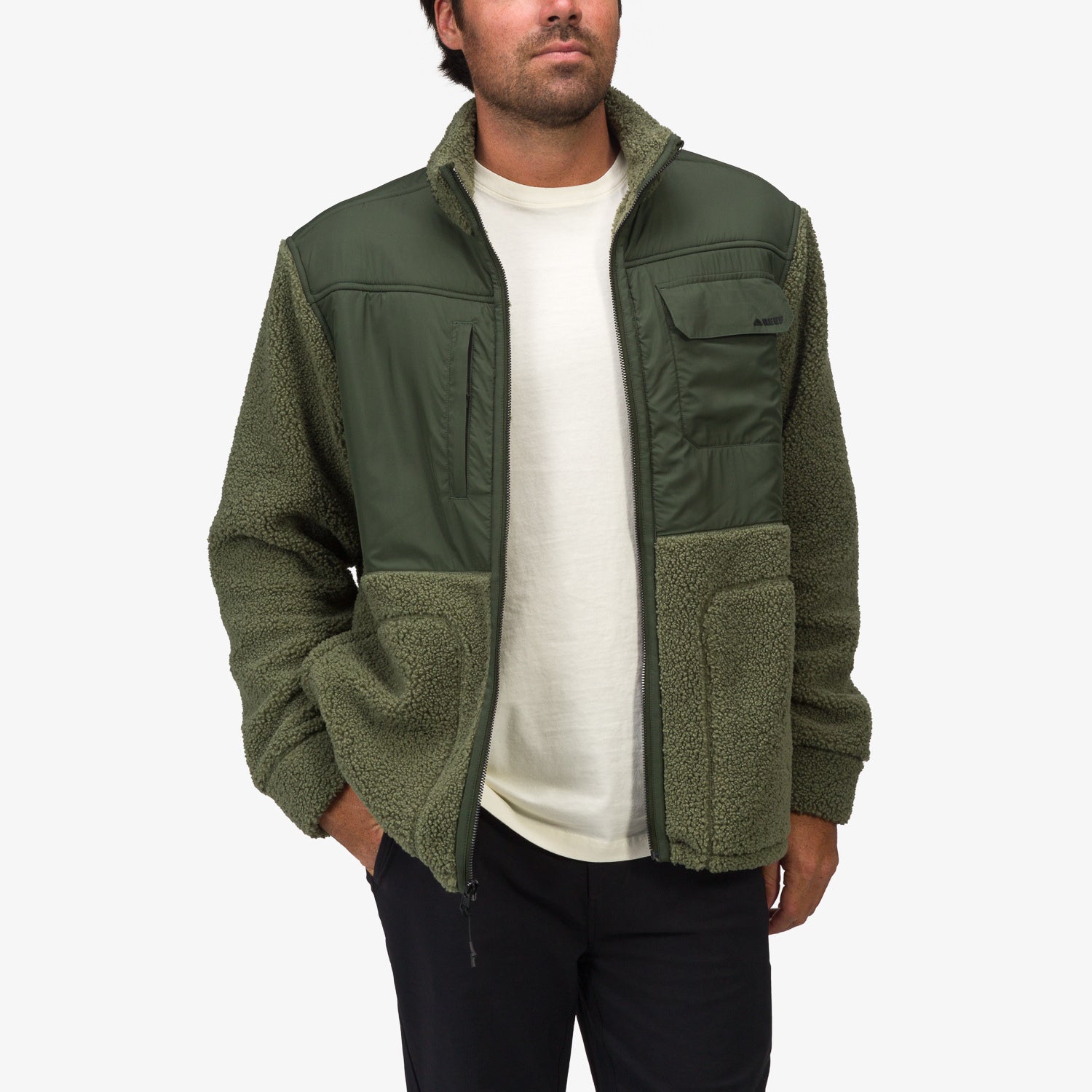 Man wearing front-facing Cooke Sherpa Jacket in green with quilted chest pockets and soft fleece sleeves and hem