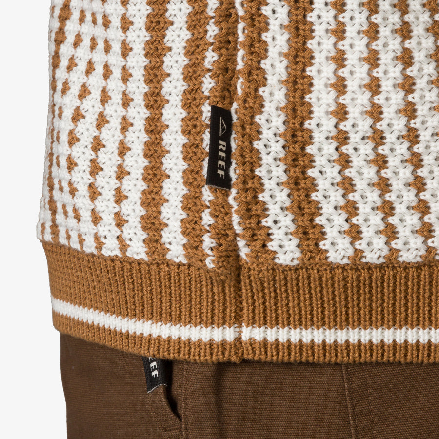 Close-up of the lower hem of the Cabana Knit Sweater in brown and white with REEF logo tag visible on the side.