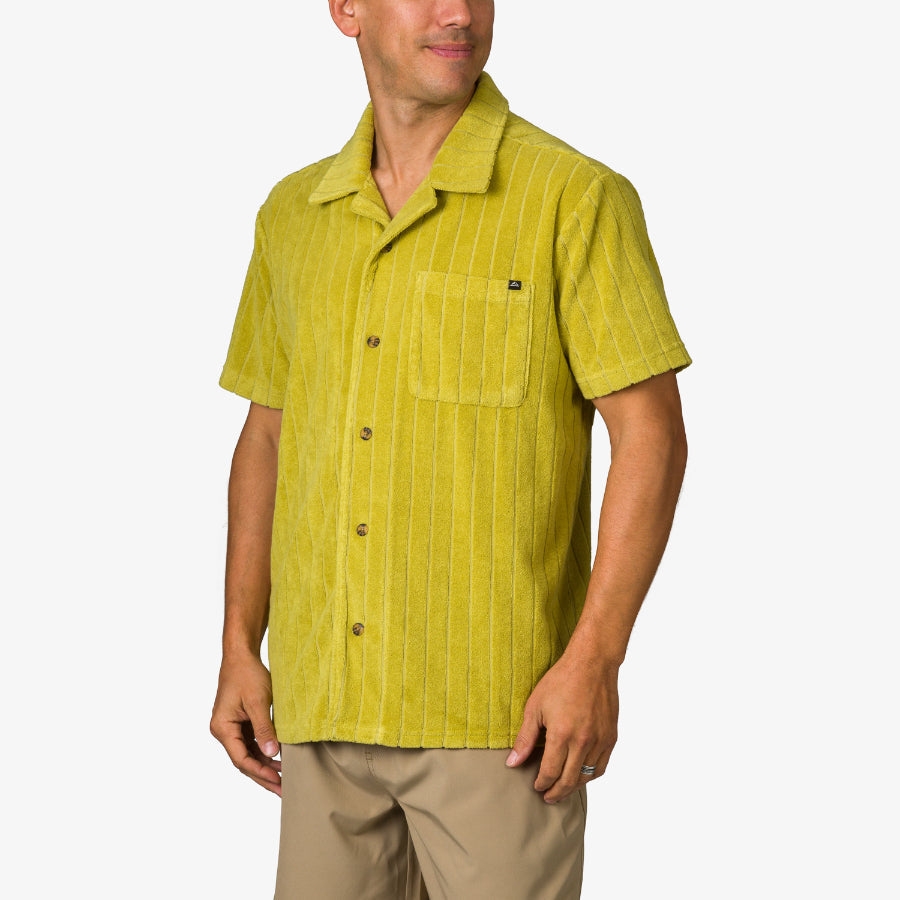 Myran Camp Shirt in mustard green with subtle stripes, front chest pocket, worn by a man facing slightly left.