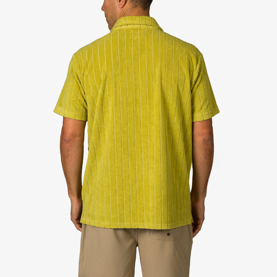 Rear view of adult man wearing lime green Myran Camp Shirt with subtle vertical stripes, designed for beach comfort and style.