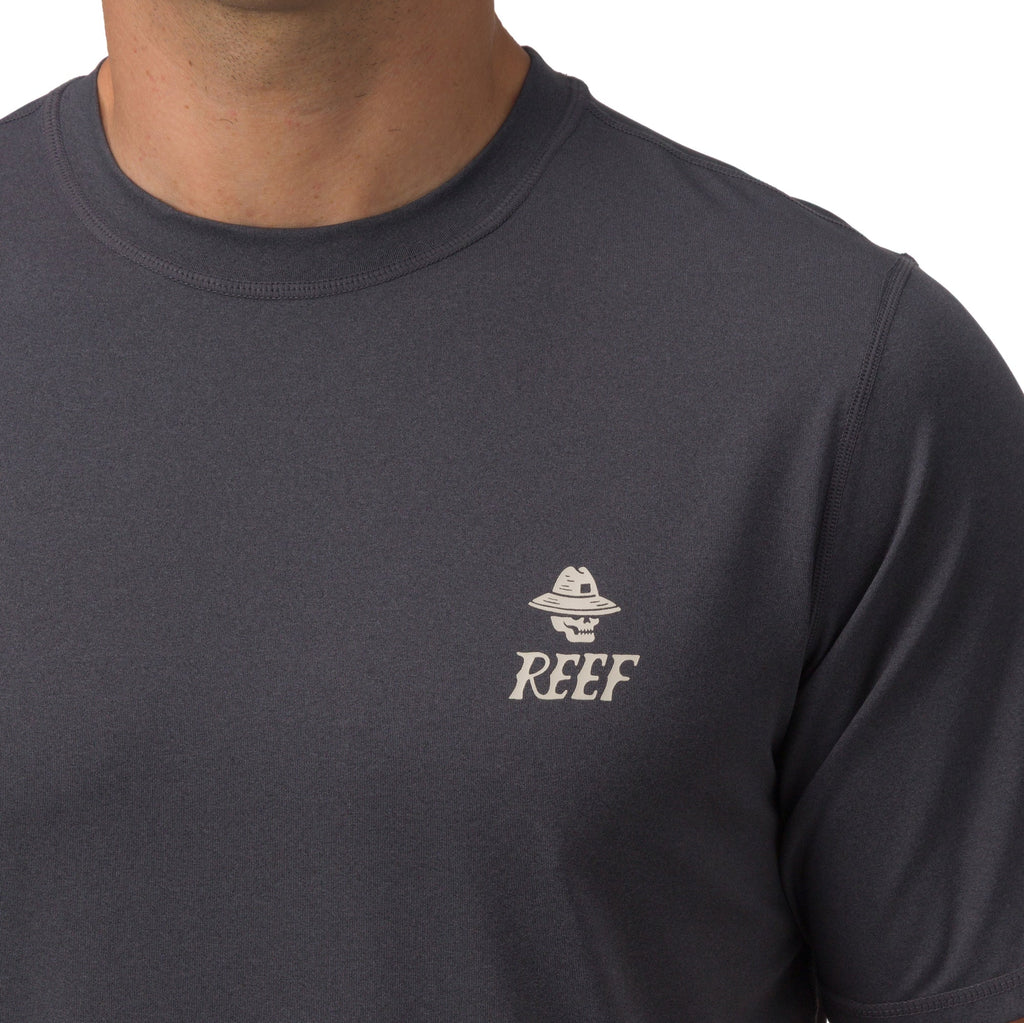 Close-up of a man wearing a dark grey Siesta Performance Shirt featuring a small REEF logo on the chest.