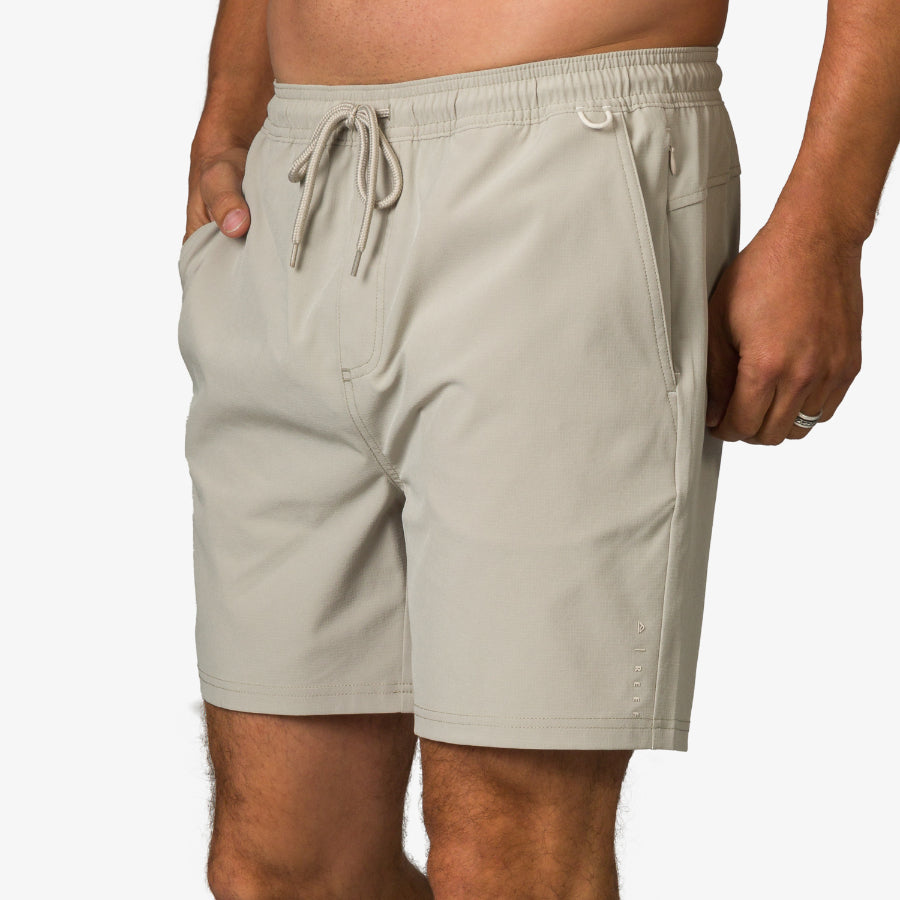 Close-up front view of men's Rushmore Hybrid Short in beige with drawstring waist and side pockets, beach-inspired comfort design.