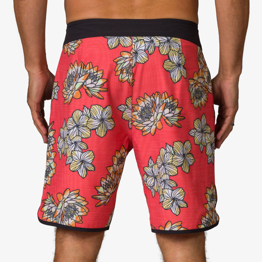 Rear view of men's Tanner Boardshort in coral with floral print and black waistband, designed for beach comfort and durability.