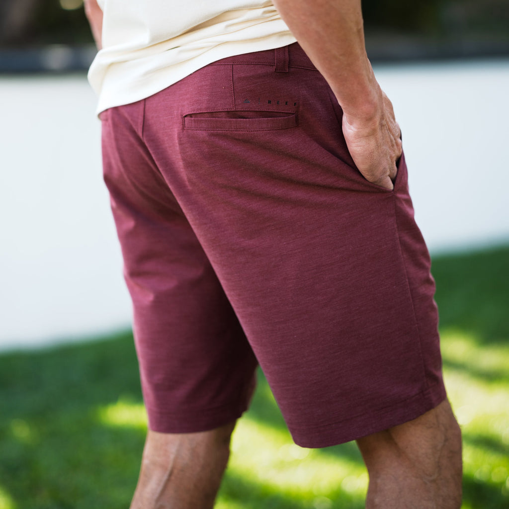 Back view of men wearing burgundy Destro Hybrid Short with hand in pocket, showcasing comfortable beach-inspired design.