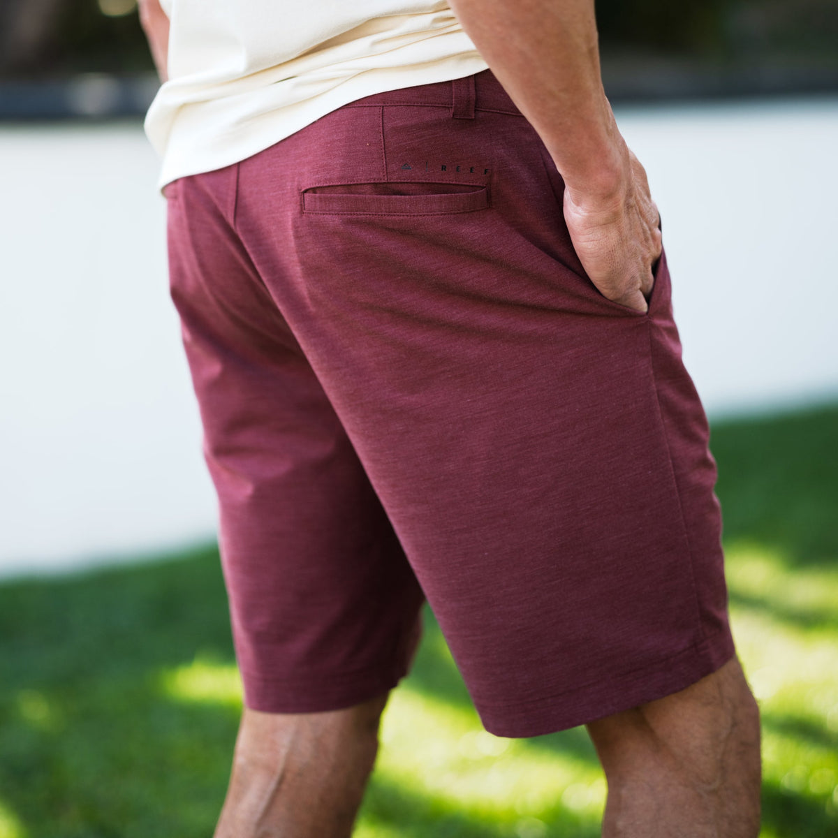 Back view of men wearing burgundy Destro Hybrid Short with hand in pocket, showcasing comfortable beach-inspired design.