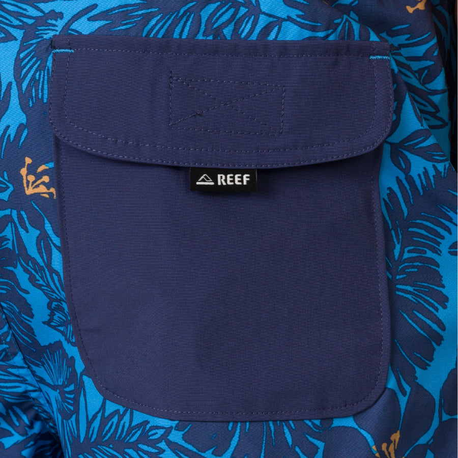 Close-up of the navy pocket with REEF logo on the blue and orange patterned Felix Boardshort for men, facing forward.