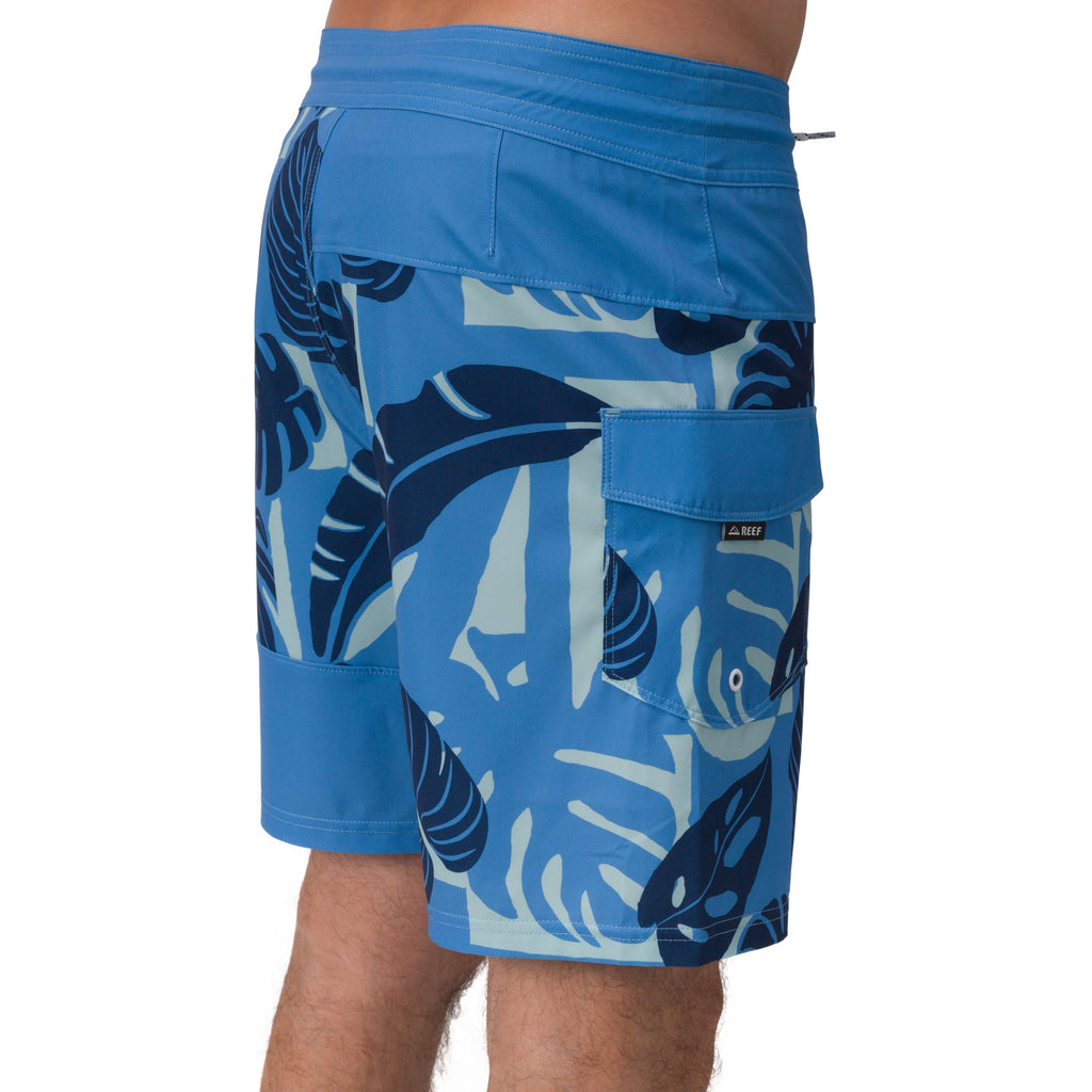Side view of men's Gonzo Boardshort in blue with leaf patterns and a rear right pocket, designed for comfort and beach life.