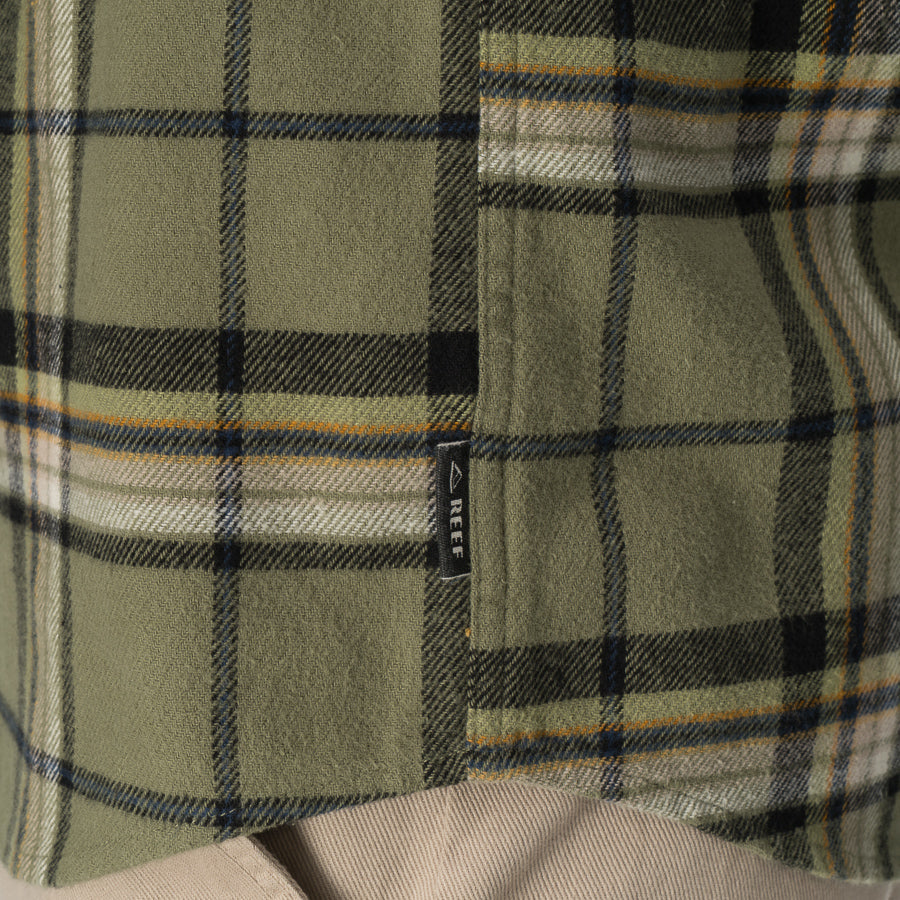 Close-up of the hem and pocket of the olive and black plaid Dyson Flannel Shirt for men, showing soft fabric texture.