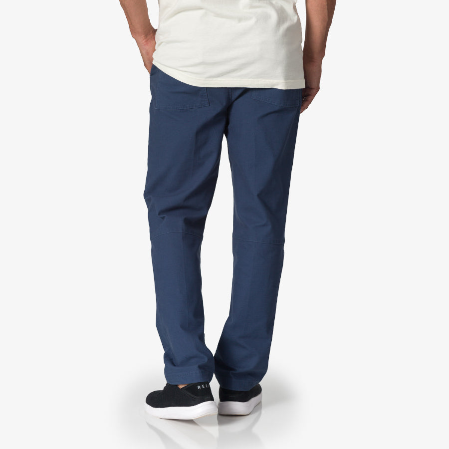 Rear view of a man wearing blue Matthew Twill Pant with black REEF sneakers facing away, showcasing comfort and casual style.
