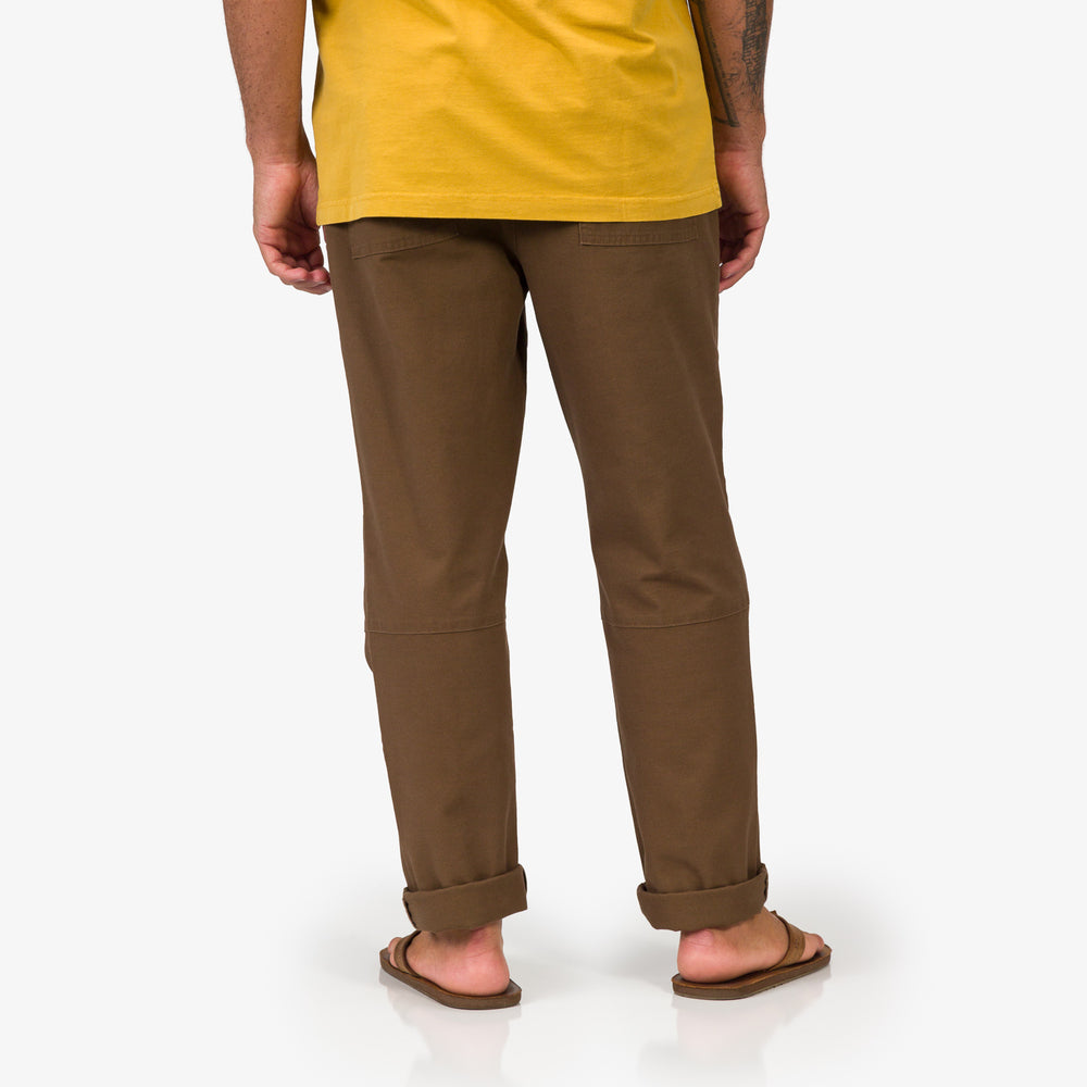Back view of a man wearing brown Matthew Twill Pant and sandals, highlighting comfort and beach-inspired casual style.