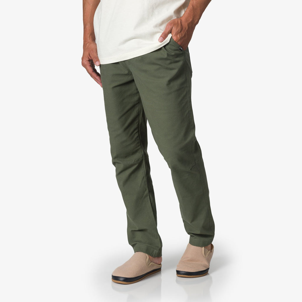 Front view of men's Matthew Twill Pant in olive green paired with beige slip-on shoes, highlighting beach-inspired comfort.