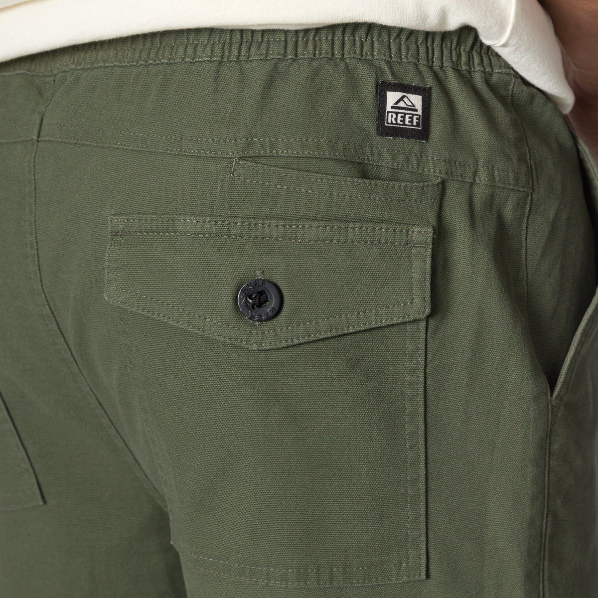 Close-up of the back pocket and waistband on men's Matthew Twill Pant in green, showcasing durable, comfortable apparel.