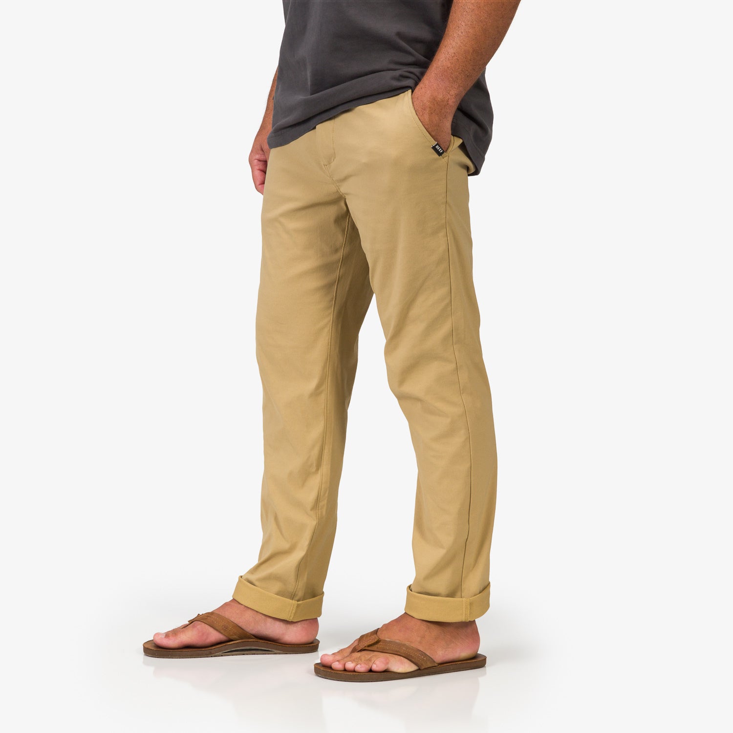 Men wearing Carrick Stretch Pant in khaki facing left, shown from mid-thigh down with sandals, beach-inspired comfort apparel.