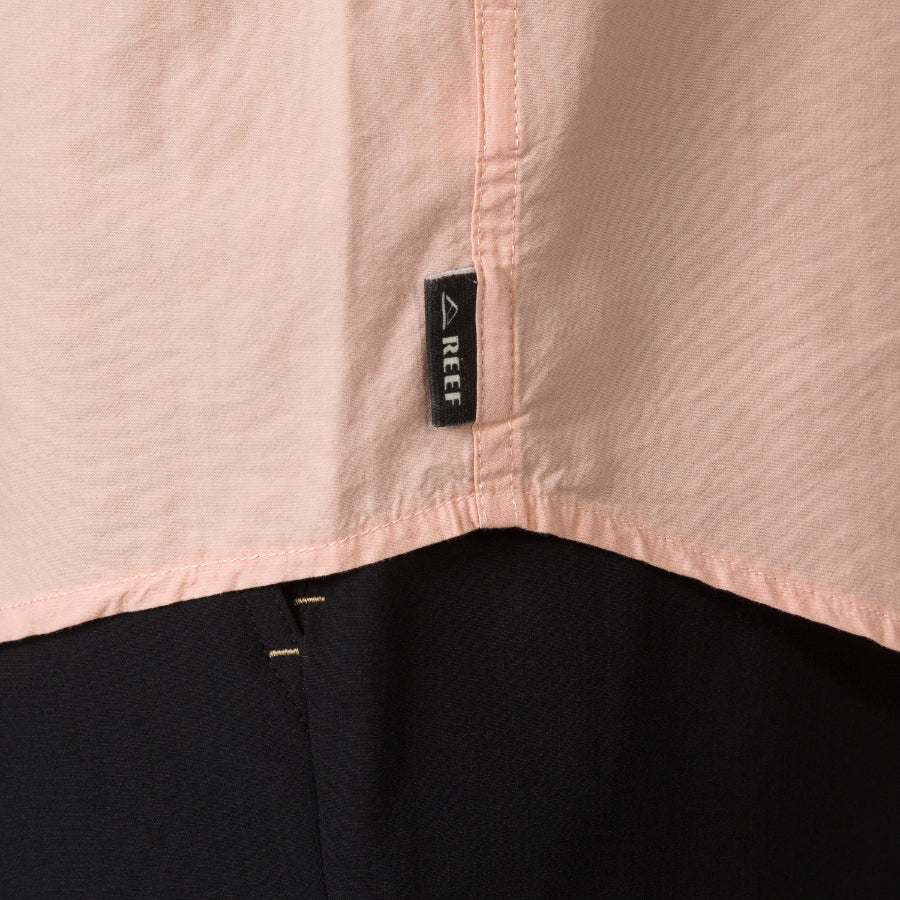 Close-up of the hem and REEF label on the Collins Ss Woven Shirt in soft peach, showcasing surf-inspired apparel detail.