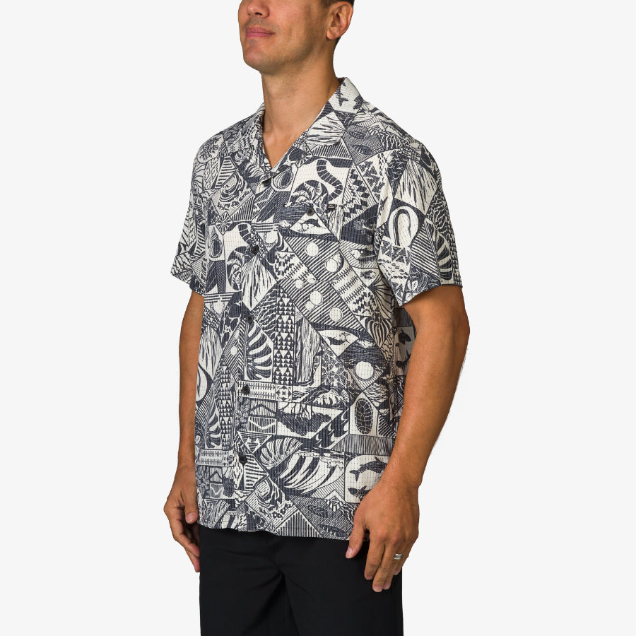 Man wearing a patterned Beckham Camp Shirt with short sleeves, designed for adults, shown from the front side angle.