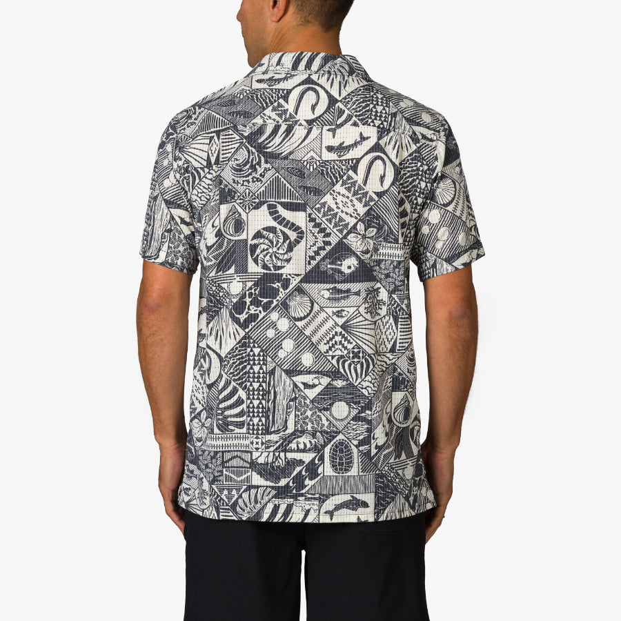 Back view of Beckham Camp Shirt on a man, featuring a monochrome tropical patchwork pattern for beach comfort.