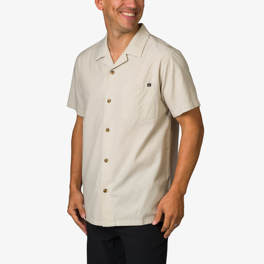 Man wearing a beige Harold Camp Shirt with button front and chest pocket, facing slightly right, smiling naturally.