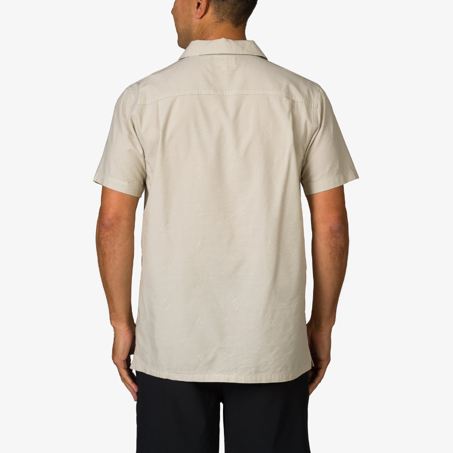 Man wearing a beige Harold Camp Shirt shown from the back, highlighting its casual, beach-inspired design.