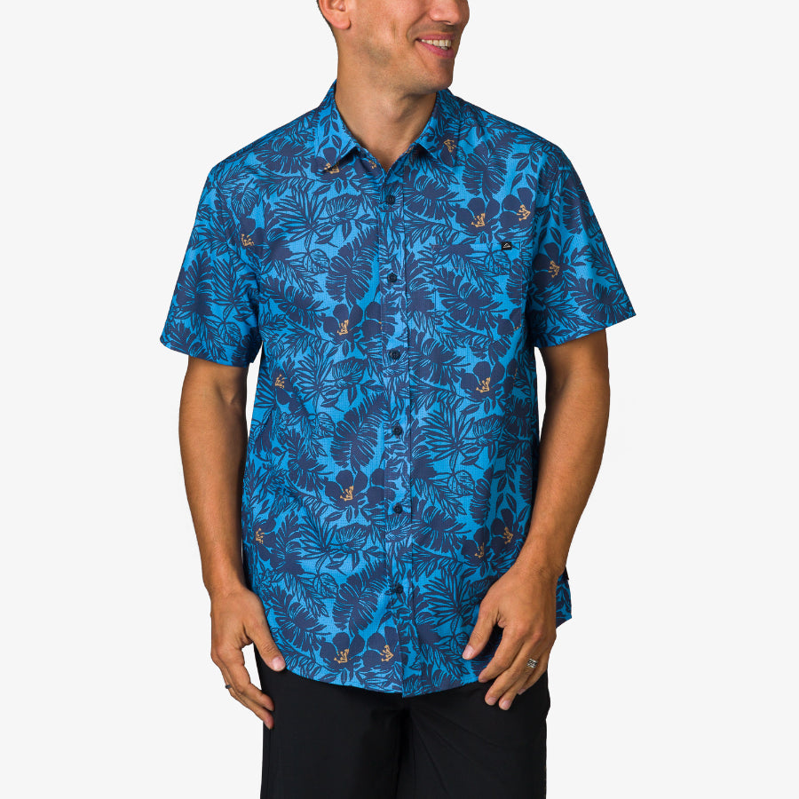 Man wearing a blue Tyson Classic Shirt with tropical print, front view, styled for beach and active lifestyles.