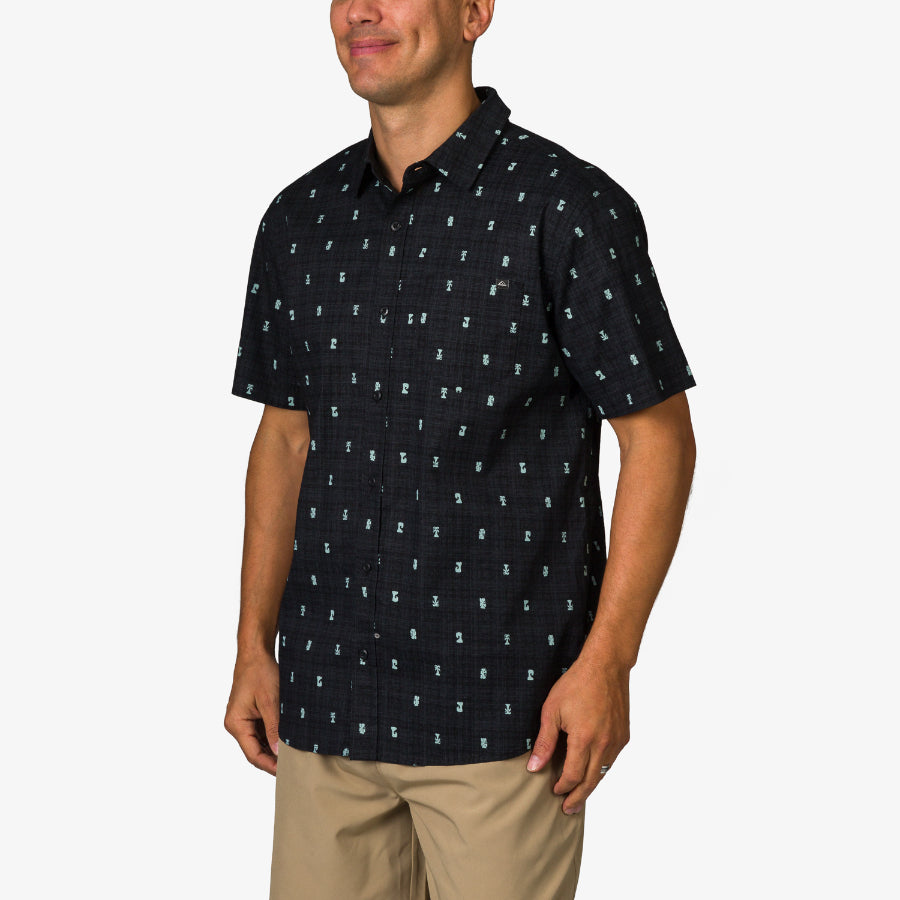 Man wearing black Chaplin Classic Shirt with small blue patterns, shown from front right side, beach-inspired comfort apparel.