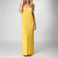 Woman wearing a yellow Plisse Dress with spaghetti straps, standing and smiling, showcasing flowy beach-inspired apparel.