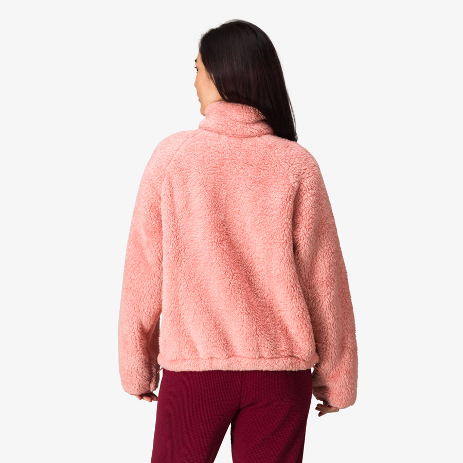 Woman wearing a pink Pilot Sherpa Jacket shown from the back, highlighting its soft, comfortable fabric and beach-inspired style.
