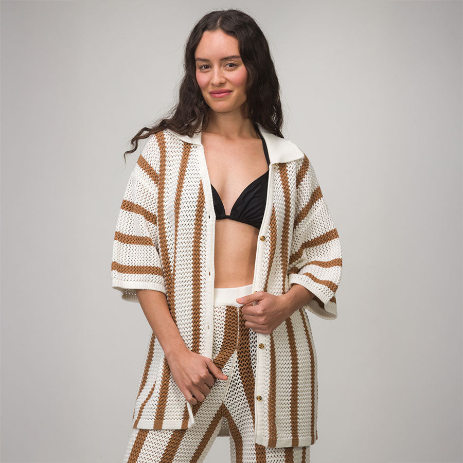 Woman wearing a Mika Button Down Top in white and brown stripes, styled beach-inspired with black bikini top underneath