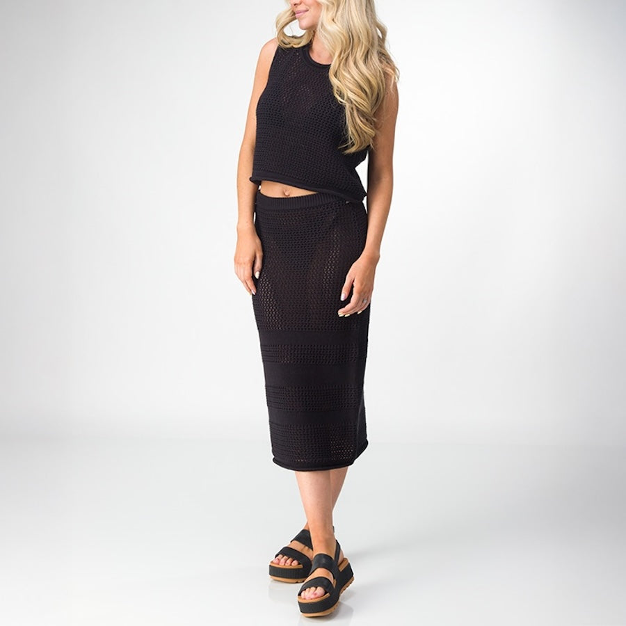 Woman wearing black Mika Sweater Tank with matching skirt and black platform sandals facing forward, beach-inspired comfort style.