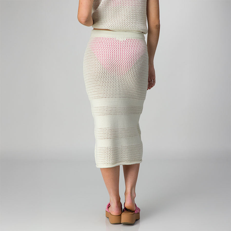 Woman wearing Mika Sweater Skirt in white with pink platform sandals facing back, showcasing skirt’s knit detail and fit.