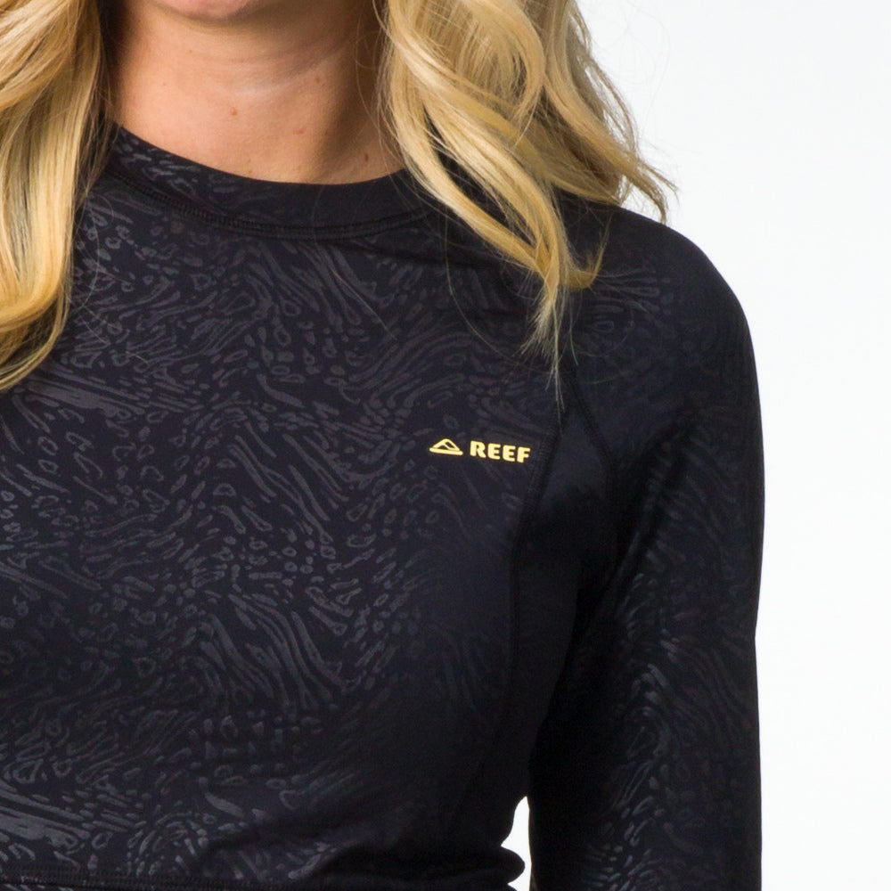 Close-up of a woman wearing a black Flex Performance Shirt with subtle pattern, emphasizing comfort and beach-inspired style.