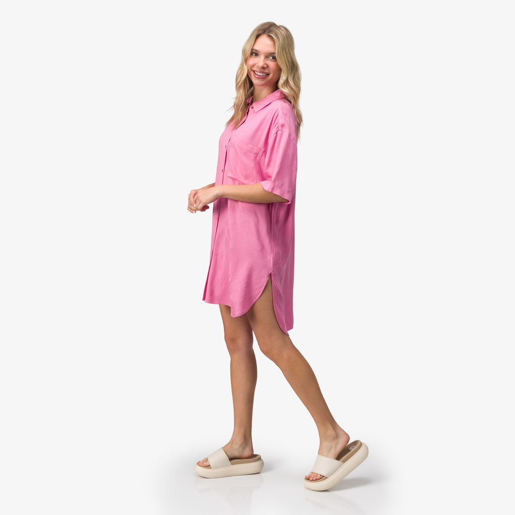 Woman wearing a pink Ollie Shirt Dress walking in beige REEF slides with anatomical arch support facing right side.