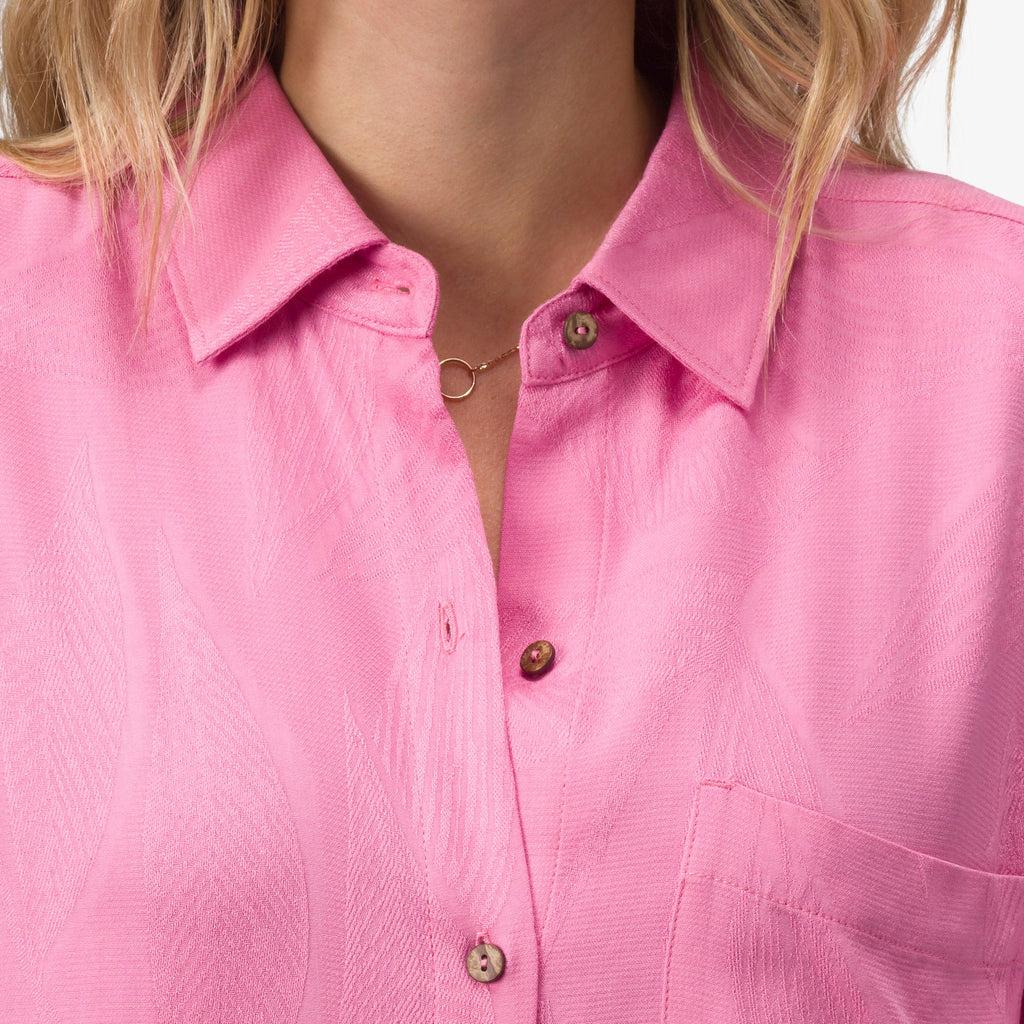Close-up of the collar and chest pocket of the pink Ollie Shirt Dress showing textured fabric and wooden buttons.