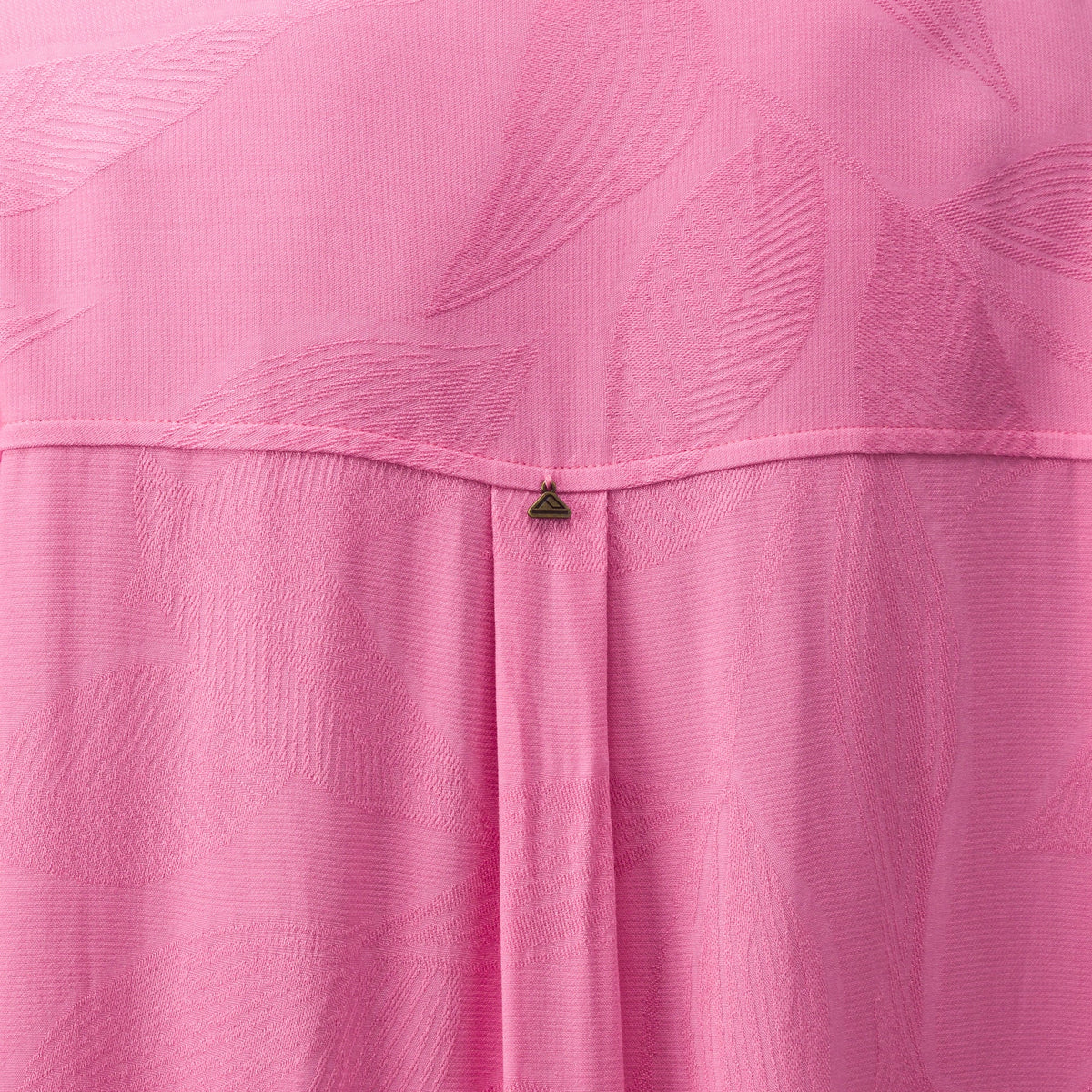 Close-up of pink Ollie Shirt Dress fabric showing textured leaf pattern and small metal logo detail on the back panel.