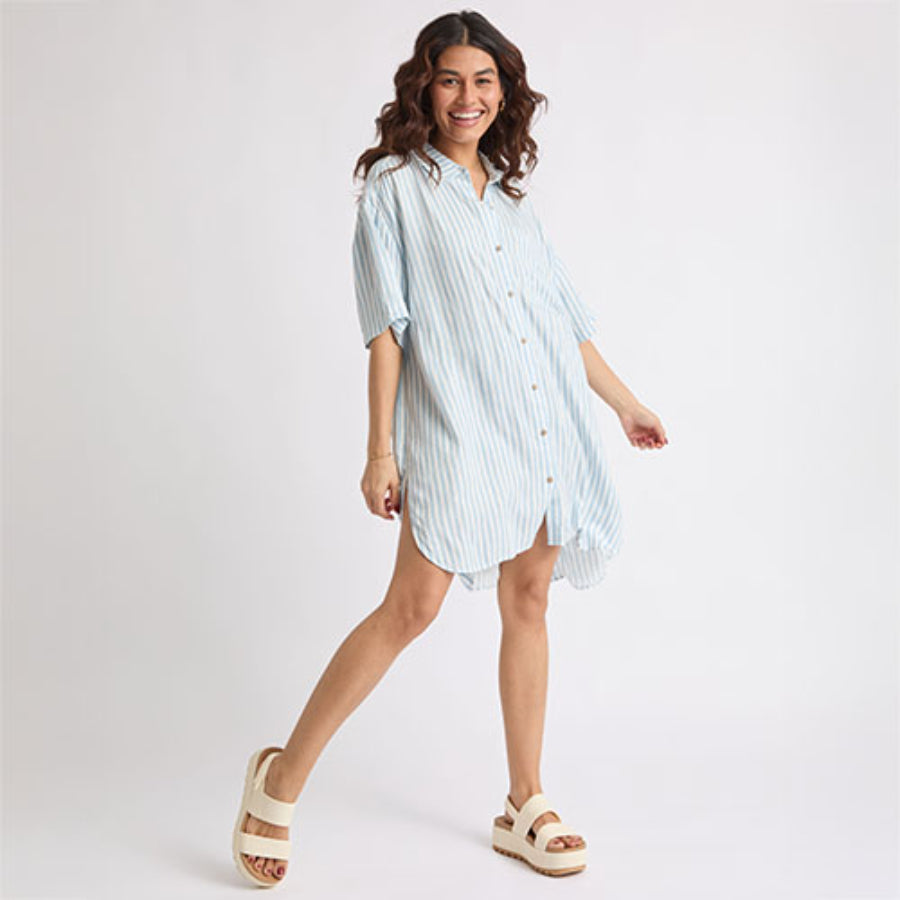 Woman wearing Ollie Striped Shirt Dress with light blue stripes, posing with left foot facing forward in white platform sandals