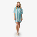 Woman wearing Ollie Shirt Dress in blue and white stripes, front view, paired with beach-inspired sandals facing forward.