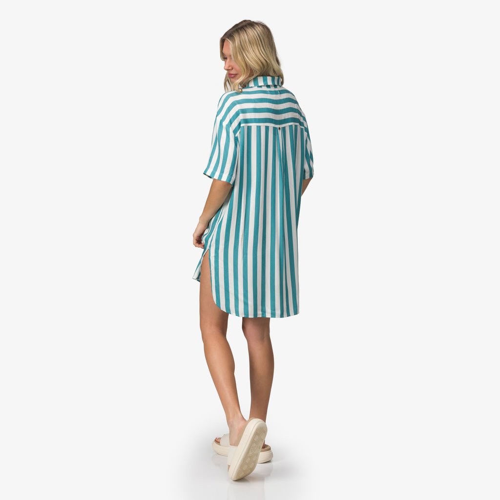 Woman wearing Ollie Shirt Dress with blue and white stripes, shown from back, walking in white REEF sandals facing right