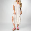 Woman wearing an Irina Shirt Dress in light beige with side slit details, paired with pink platform sandals facing forward.