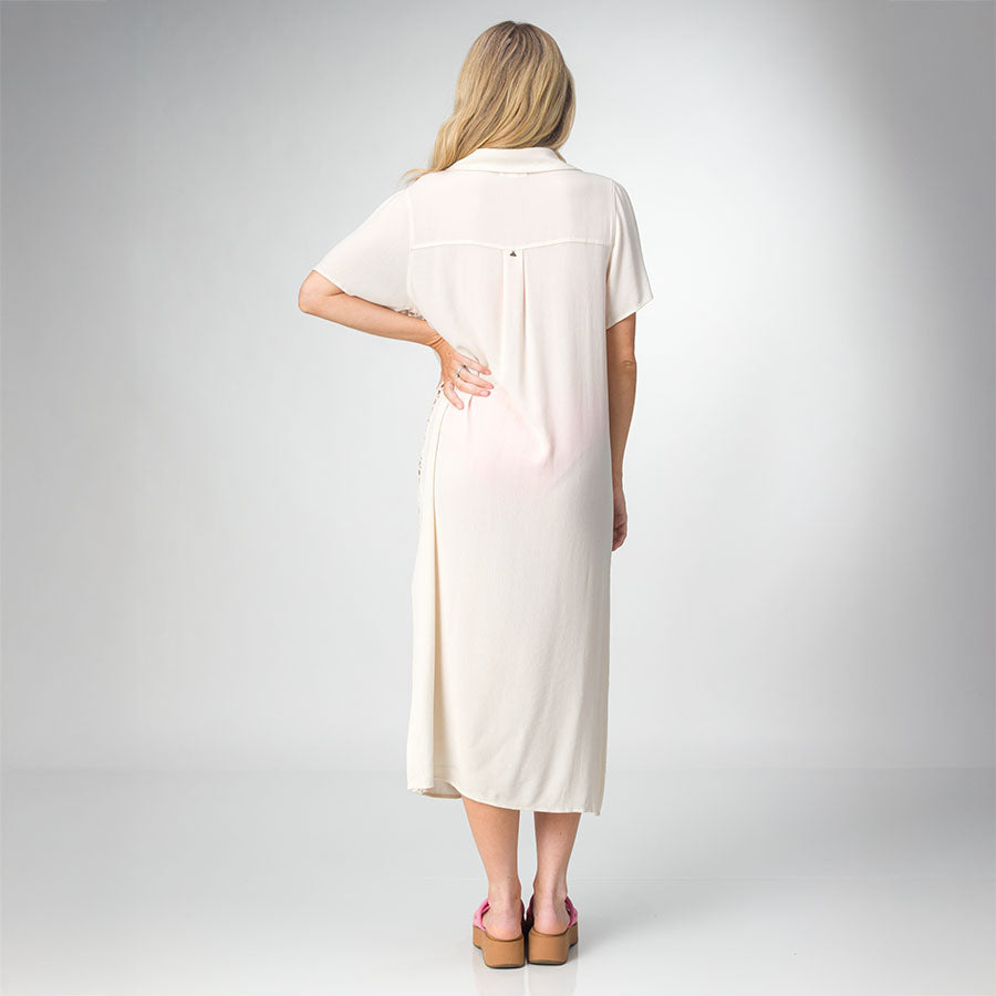 Woman wearing a cream-colored Irina Shirt Dress, shown from the back with pink platform sandals facing backward.