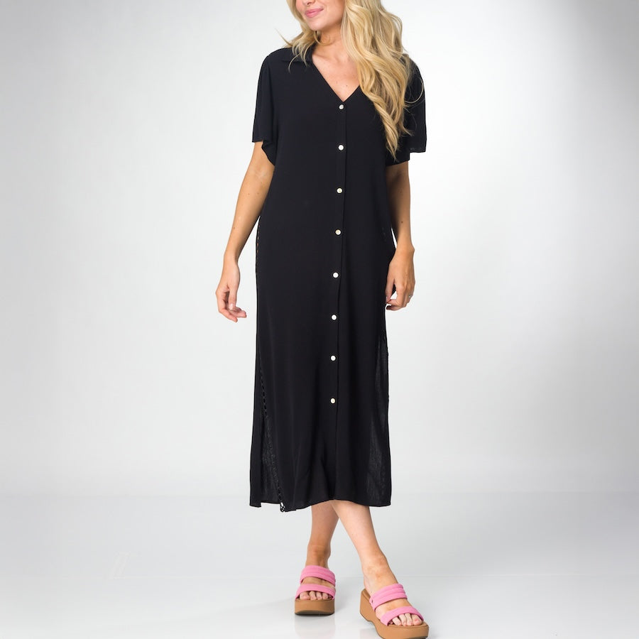 Woman wearing a black Irina Shirt Dress with short sleeves and buttons down front, paired with pink platform sandals facing forward.