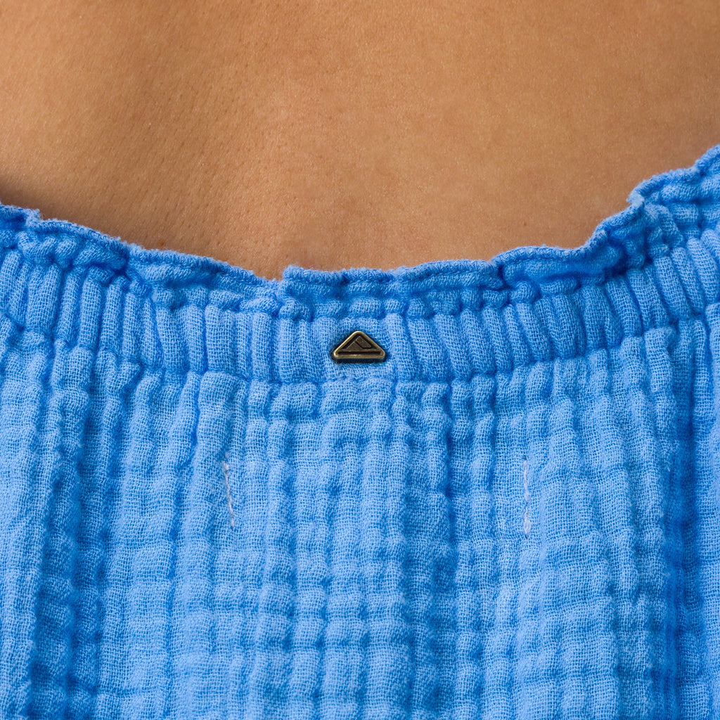 Close-up of the top back of the Lainey Maxi Dress in soft blue fabric with a small metal logo detail.