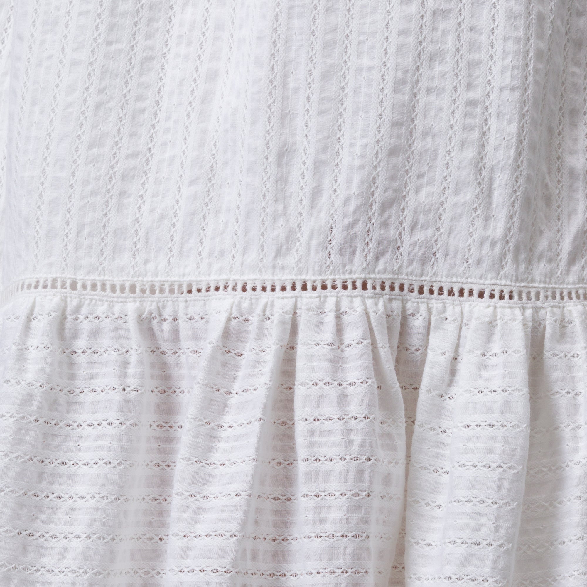 Close-up of white Yuni Maxi Dress fabric showing textured eyelet and delicate stitching details.