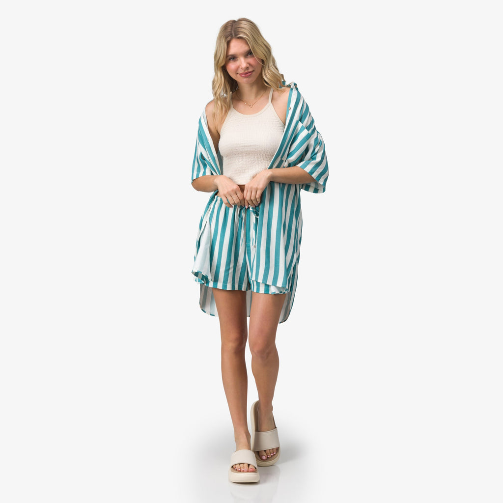 Woman wearing Ollie Shirt Dress in teal stripes, facing forward, styled with casual sandals for a beach-inspired look.