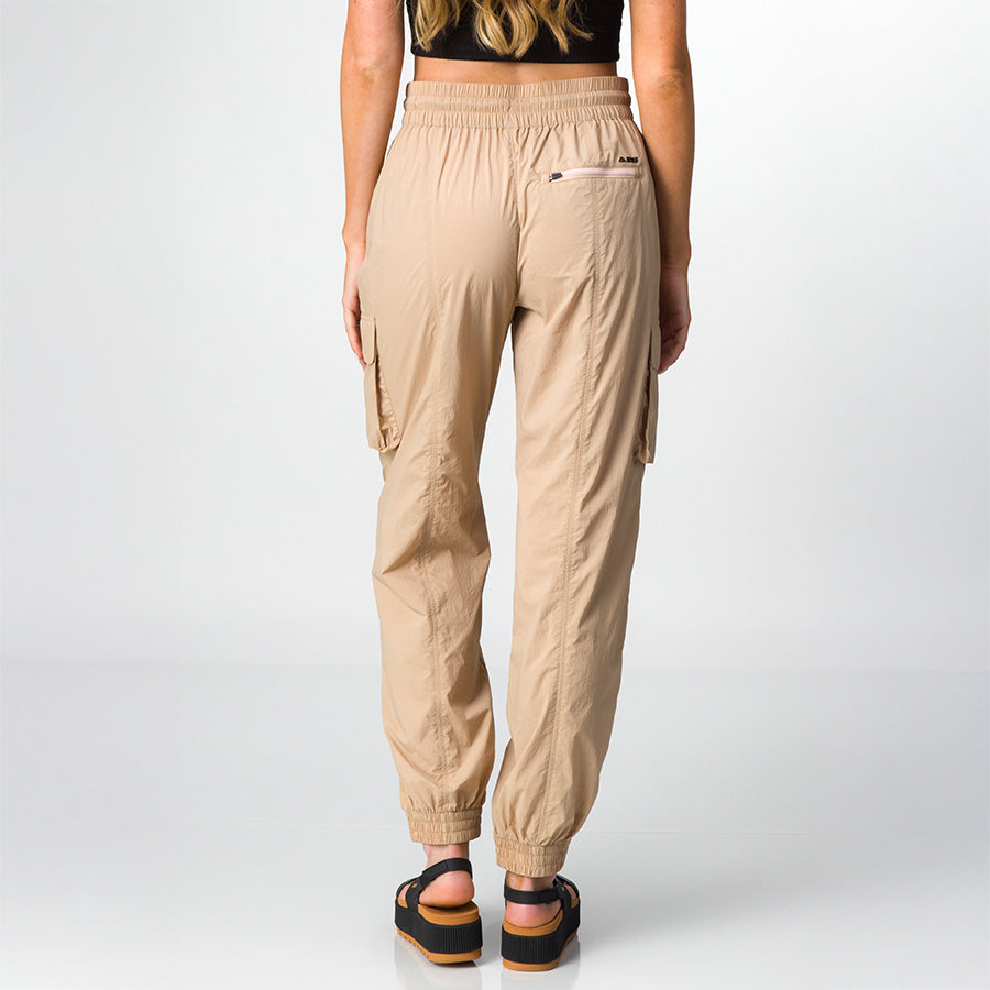 Woman wearing beige Cargo Jogger Pant shown from back, wearing black sandals facing rear, highlighting relaxed fit and pockets