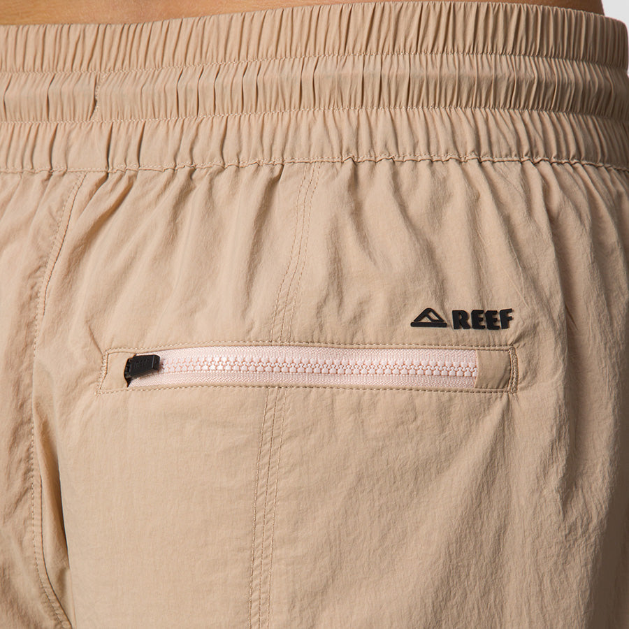 Close-up of back pocket on beige Cargo Jogger Pant for women with REEF logo, beach-inspired durable apparel.
