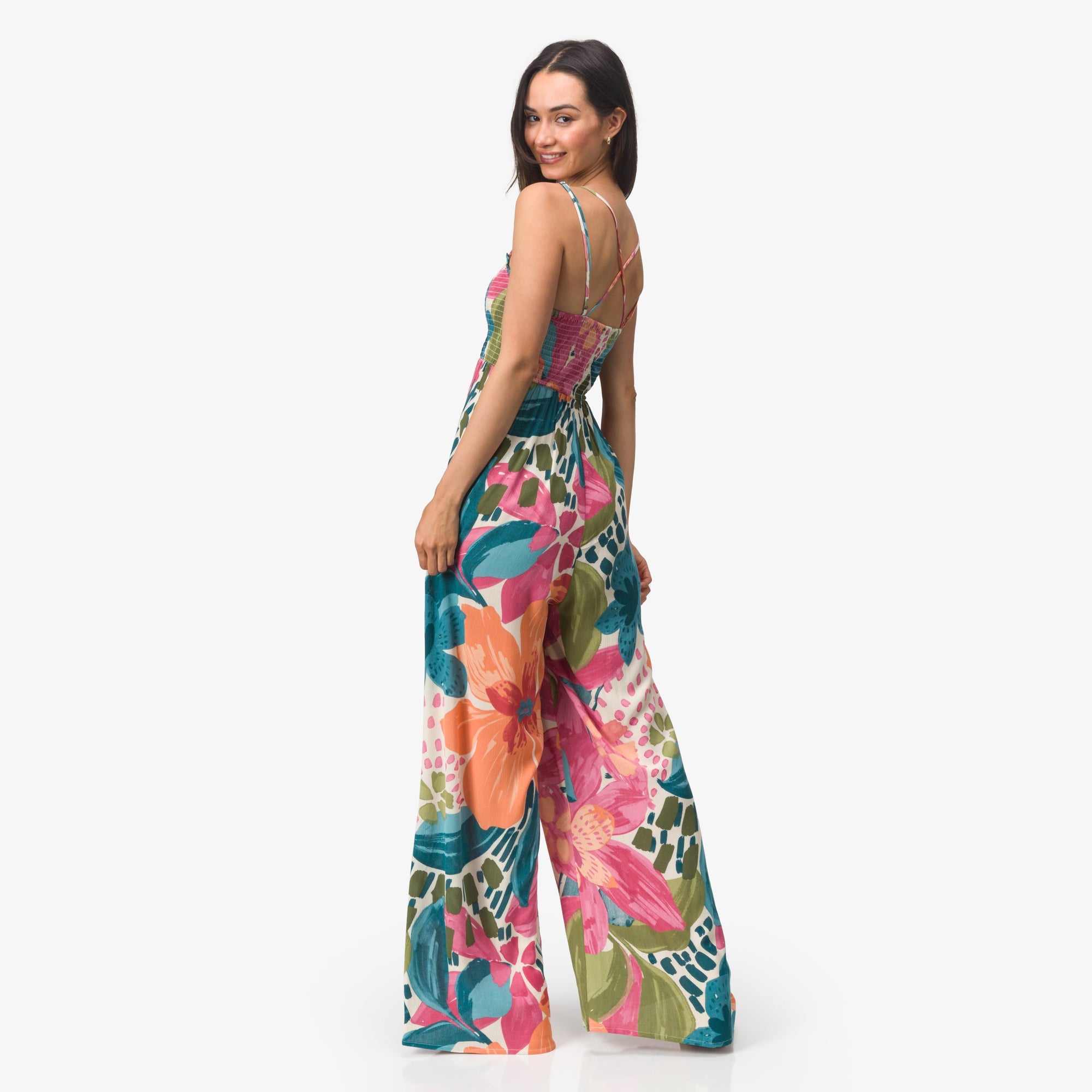Woman wearing a colorful Eve Wide Leg Romper with floral print, back view showing adjustable straps and wide legs