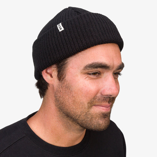 Alyx Beanie worn by a man facing right, showing the knit texture and small REEF logo tag on the cuff.