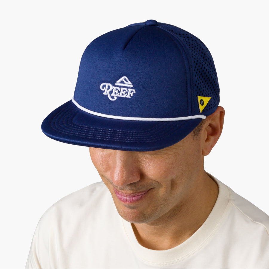 Man wearing a navy Blue Blackball Hat facing forward, showing front and side mesh panel with REEF logo detail.