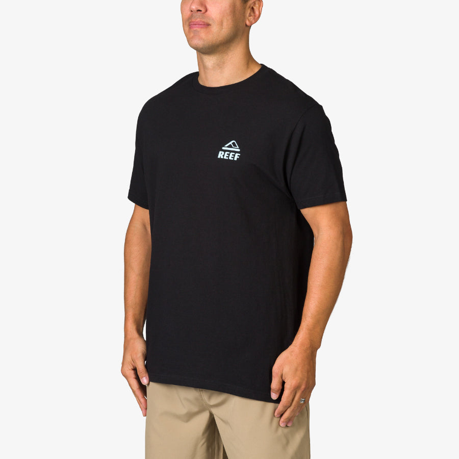Male model wearing black Strings Tee with REEF logo, front view, showcasing comfortable, beach-inspired men’s apparel.